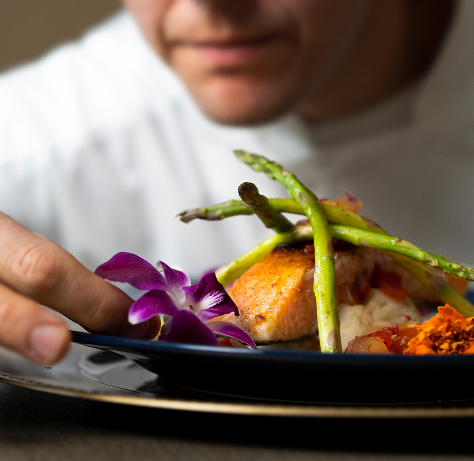 A chef putting food on a plate.